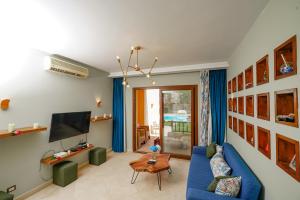 El Gouna 2 bedrooms apartment South Marina Ground Floor في الغردقة: غرفة معيشة مع أريكة زرقاء وتلفزيون