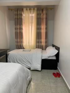 1 Schlafzimmer mit 2 Betten und 2 roten Schuhen auf dem Boden in der Unterkunft KWETU HAVEN HOMES in Kigali