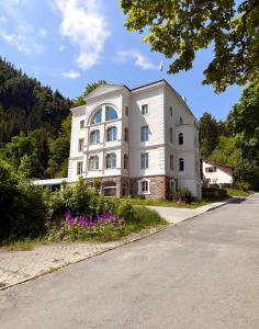 a white building with flowers in front of a road at Apartament Miła 2 Lądek-Zdrój in Lądek-Zdrój