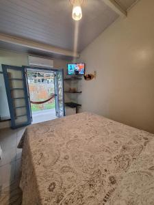 - une chambre avec un lit, une télévision et une fenêtre dans l'établissement Pousada Sobre as Pedras, à Itanhaém