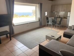 a living room with a couch and a large window at Kalamitsi House 1 in Agia Pelagia