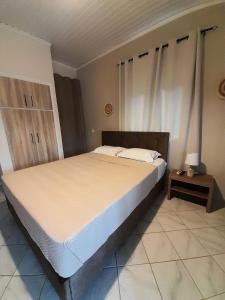 a bedroom with a large bed with a night stand at Aggeliki Apartments in Nikiana