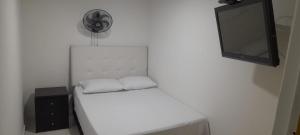 a white bed with two white pillows and a television at Hotel Mallorca Estadio, Medellin in Medellín