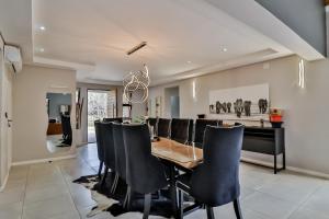 - une salle à manger avec une table, des chaises et un piano dans l'établissement House of Bongekile 4 Bed Luxury Home in Malelane, à Malelane