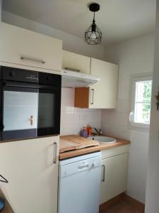 a kitchen with white cabinets and a black appliance at Entre terre et mer in Camiers +5 photos