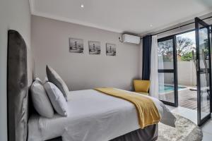 a bedroom with a white bed and a balcony at House of Bongekile 4 Bed Luxury Home in Malelane in Malelane