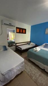 a bedroom with two beds and a blue wall at Chez Max Pousada in Morro de São Paulo