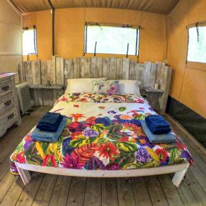 MouliherneにあるLuxury Safari Tent with Hot Tub at Camping La Fortinerieのベッドルーム1室(大型ベッド1台、カラフルな毛布付)