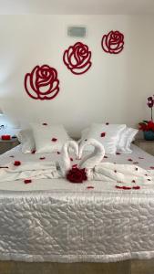 Una cama con dos cisnes y rosas. en Pousada Pé na Areia Guarujá, en Guarujá