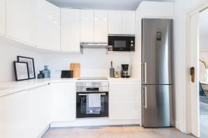 Una cocina con gabinetes blancos y un refrigerador de acero inoxidable. en Viña Vieja a pasos de la Playa, en Las Galletas