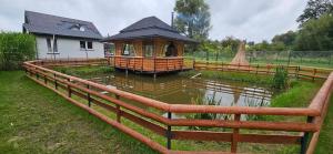 a wooden fence around a pond with a gazebo at Zacisze na Roztoczu in Horyniec