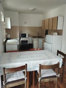 eine Küche mit einem Tisch und 2 Stühlen sowie eine Küche mit weißen Geräten in der Unterkunft Apartment Sinčić in Kastav