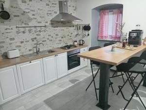 a kitchen with white cabinets and a wooden table at Kali in Kukuljanovo