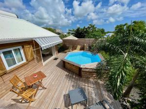 a wooden deck with a swimming pool and a house at La Papaye d’Or in Saint-François