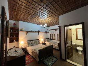 a bedroom with two beds and a bathroom with a mirror at Hotel Kaceli in Berat