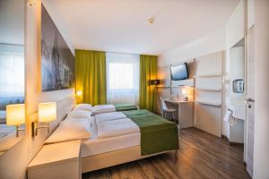 um quarto de hotel com uma cama e uma secretária em LifeHotel Vienna Airport em Fischamend Dorf