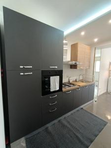a kitchen with black cabinets and a stove top oven at Monolocale Farina in Cagliari