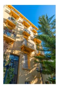 a yellow building with balconies and a palm tree at Petit Paradis in Nice