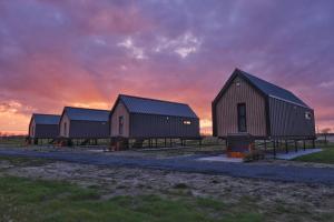 a group of barns with a sunset in the background at Wad & Loft unieke paalwoning vlakbij de Waddenzee in Pietersbierum