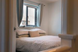 Dormitorio pequeño con cama y ventana en THE COSY HOME BY KS - Free Parking, WI-FI, Smart TV, Kitchen, Washing machine, Long Stays Welcomed, en Hereford