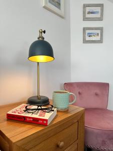 a lamp sitting on top of a book on a table at Sea Walk Cottage, Milford On Sea in Milford on Sea
