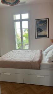 een witte slaapkamer met een bed en een raam bij Petit Paradis in Nice