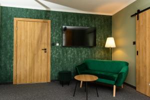 ein Wohnzimmer mit einem grünen Sofa und einem TV in der Unterkunft Noclegi na Wspólnej 