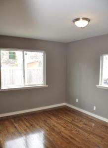 Sherwood Cottage - Steps from Old Town & Poudre River في فورت كولينز: غرفة معيشة فارغة بها نافذتين وأرضية خشبية