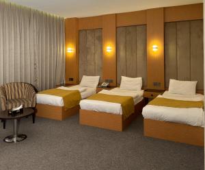 a hotel room with three beds and a chair at MyHotel Erbil in Erbil +51 photos