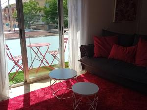 a living room with a couch and tables and a balcony at El estudio de las mariposas,sofa cama , cocina y baño in Partida de La Cañada