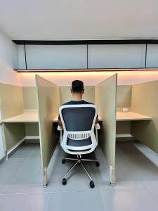 einem Mann, der auf einem Stuhl an einem Schreibtisch sitzt in der Unterkunft Reset (Hotel-Cafe-Coworking) in Cali