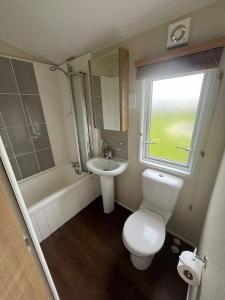 a bathroom with a toilet and a sink and a tub at Golden Anchor - The Vogue - Coastal Caravan Breaks in Chapel Saint Leonards