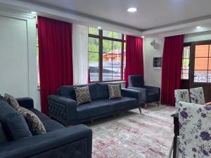 a living room with blue couches and red curtains at Uzungöl Kuzey Park Pansiyon in Uzungöl