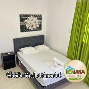 - une petite chambre avec un lit et un rideau vert dans l'établissement IGUANA HAUS IQUITOS, à Iquitos