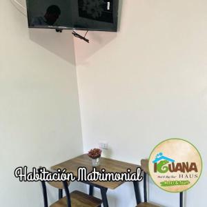 une table avec une chaise et une télévision murale dans l'établissement IGUANA HAUS IQUITOS, à Iquitos