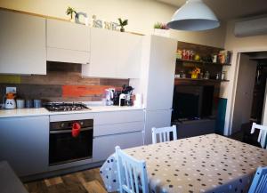 cocina con armarios blancos, mesa y fogones en Casa Camilla, en Grosseto 2 fotos más