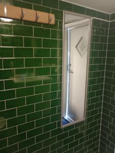 a mirror in a green tiled bathroom at Ackes Stuga 32 in Örebro