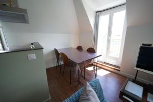 una sala da pranzo con tavolo, sedie e finestra di Appartement de Paul ad Aurillac