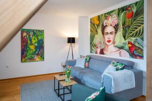 a living room with a blue couch and a large painting at NAMASTÉ Homes - Ferienwohnung mit Dachterrasse in Bad Windsheim +19 photos