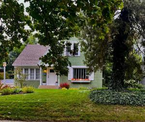 a green house with a white door and a window at Cozy Cape Cod in Grand Rapids