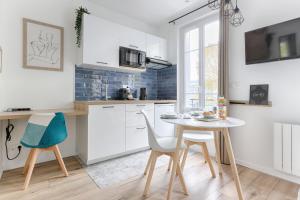 - une cuisine avec des placards blancs, une table et des chaises dans l'établissement Studio Cosy face gare RER A, à Sucy-en-Brie