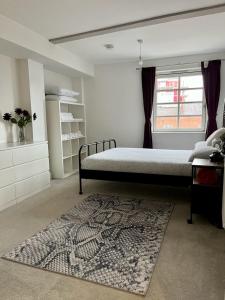 a bedroom with a bed and a rug and a window at Huller and cheese warehouse apartments in Bristol