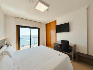 1 dormitorio con cama, escritorio y ventana en Hotel Mardevela en Sanxenxo