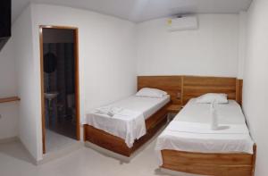 2 Betten in einem Zimmer mit Spiegel in der Unterkunft HOTEL VINCCI in Chigorodó