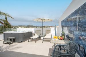 a patio with a table and chairs and an umbrella at JnS Premium Stay in Faliraki