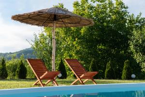 two chairs and an umbrella next to a swimming pool at Zelinjski vidikovac in Zvornik