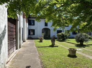 a courtyard of a white building with trees and grass at Casale Brambilla in San Zenone al Po