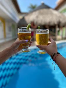 two people holding up glasses of beer by a pool at Hotel Casa Grande Riohacha Inn in Ríohacha