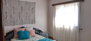 een slaapkamer met een bed met kussens en een raam bij Casa Golfinho (Norte) - Costa Nova in Costa Nova