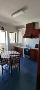 een keuken met een tafel en een fornuis bovenste oven bij Casa Golfinho (Norte) - Costa Nova in Costa Nova